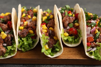 Photo of Delicious tacos with meat and vegetables on table, closeup