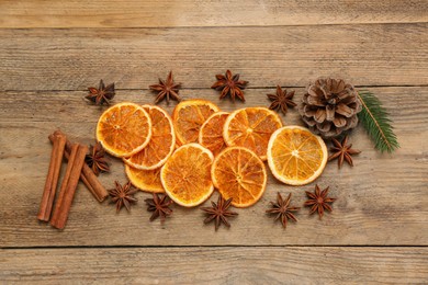 Photo of Dry orange slices, cinnamon sticks, fir branch and anise stars on wooden table, flat lay