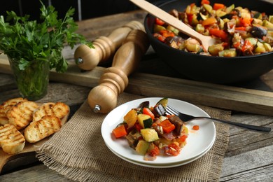 Delicious ratatouille served with bread on wooden table