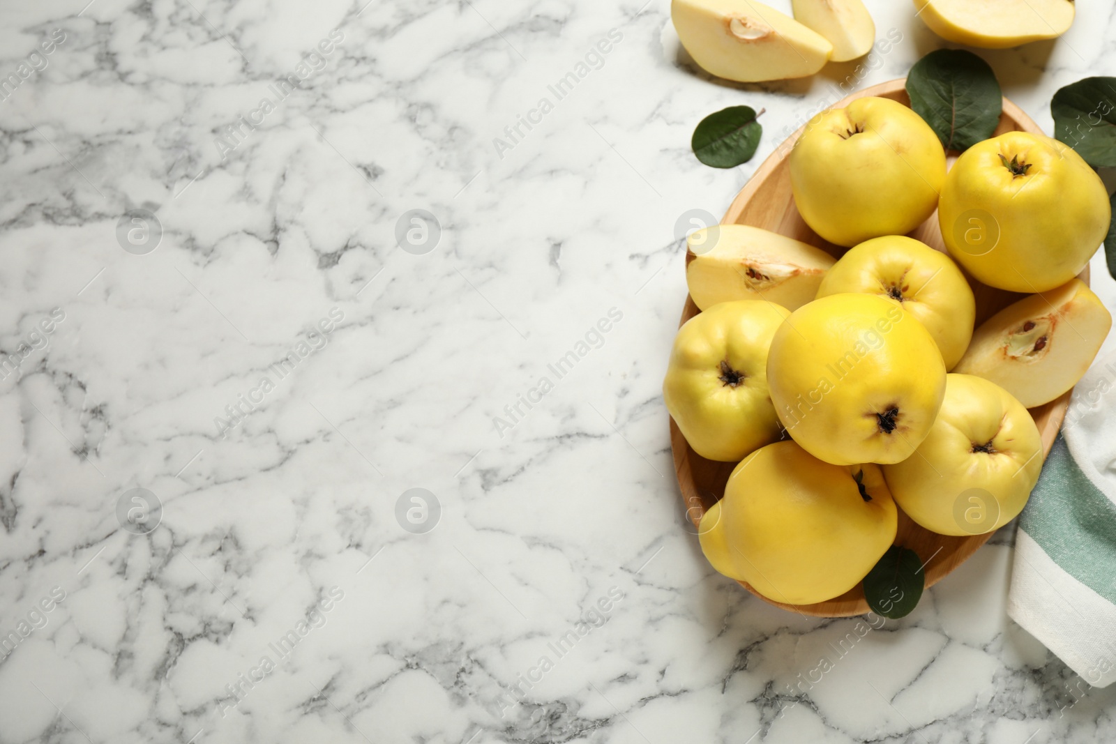 Photo of Fresh ripe organic quinces with leaves on white marble table, flat lay. Space for text