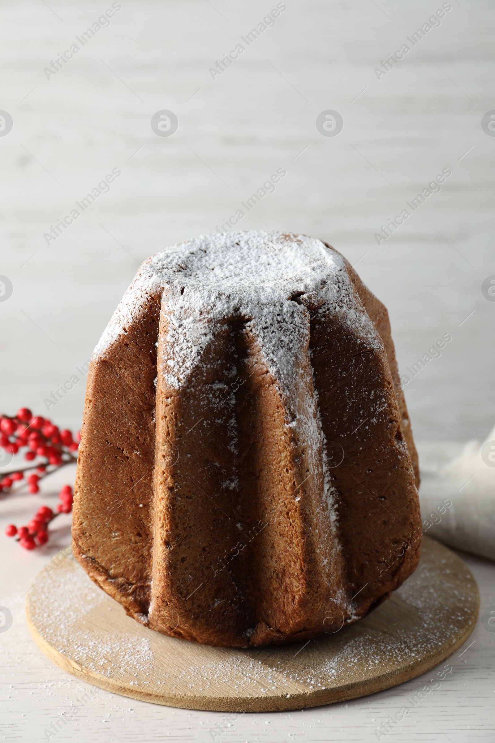 Photo of Delicious Pandoro cake decorated with powdered sugar on white wooden table. Traditional Italian pastry