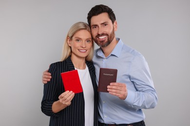 Immigration. Happy couple with passports on gray background