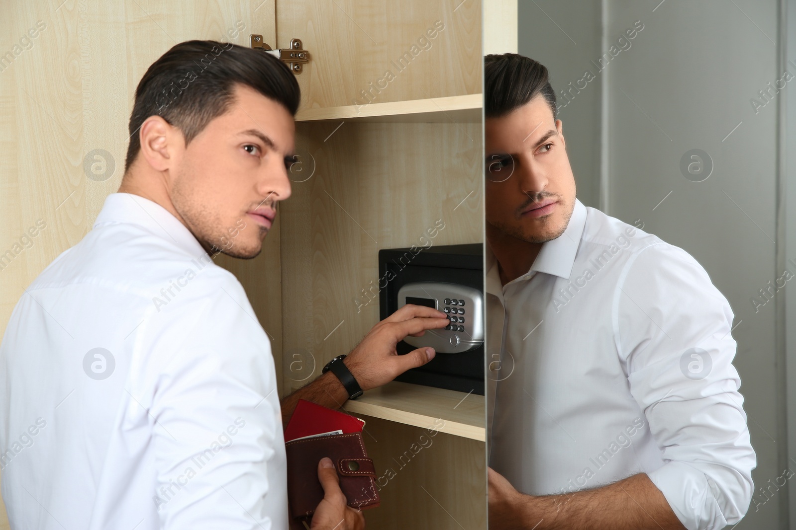 Photo of Man opening black steel safe with electronic lock at hotel