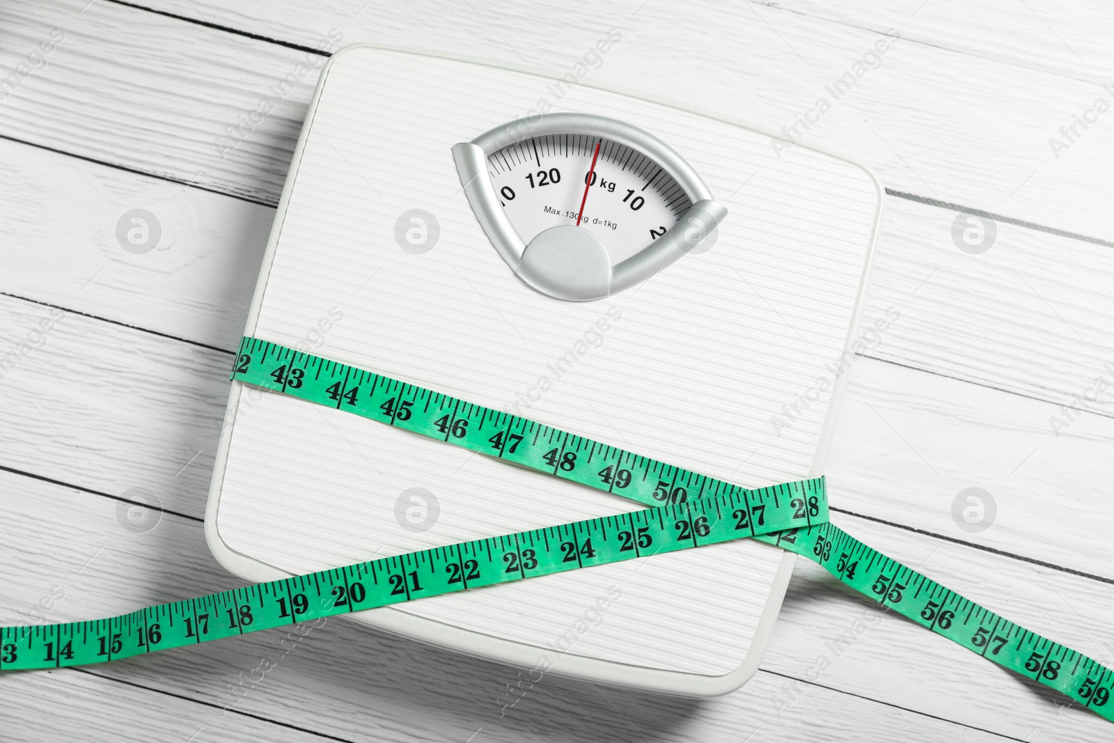 Photo of Scales with measuring tape on white wooden background, top view. Weight loss concept