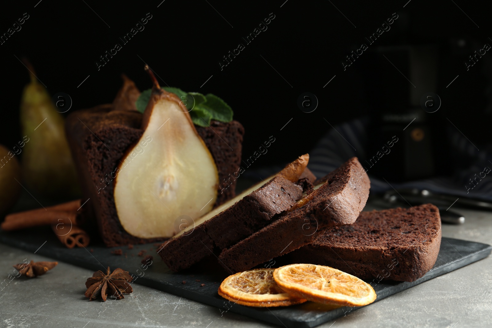 Photo of Tasty pear bread with spices, dried orange slices and mint on grey table. Homemade cake