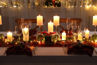 Photo of Christmas table setting with burning candles and festive decor