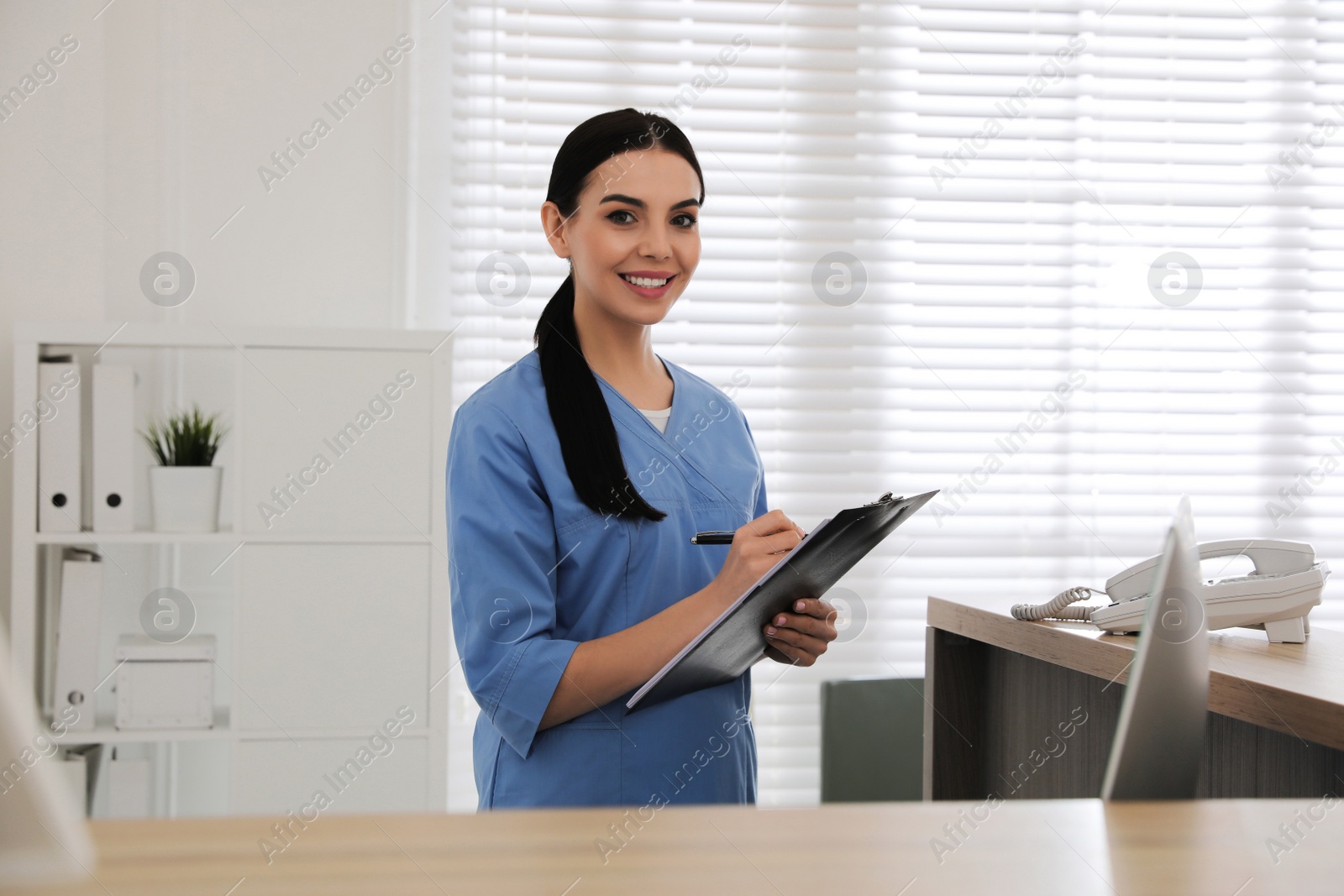 Photo of Receptionist with clipboard at countertop in hospital