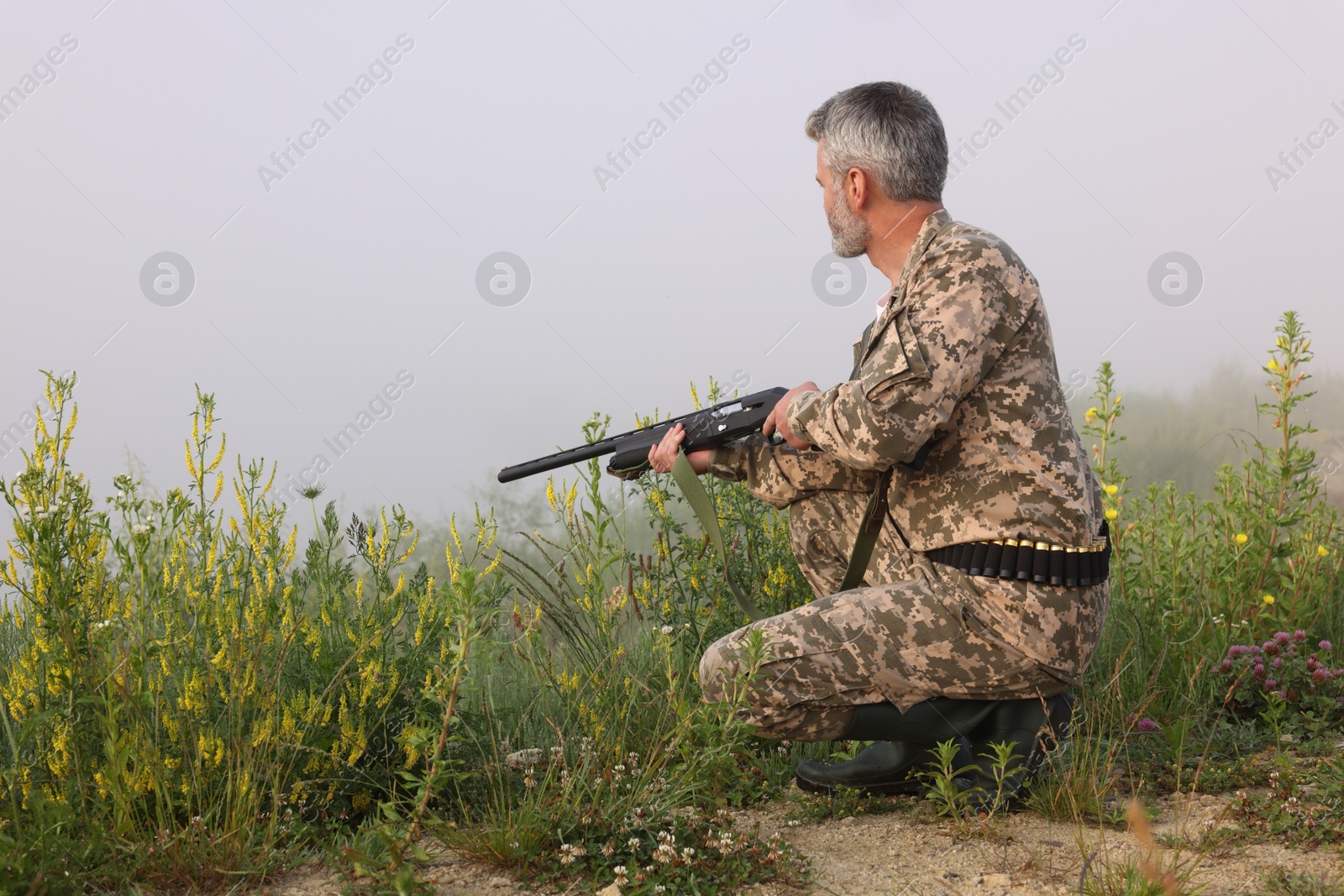Photo of Man wearing camouflage with hunting rifle outdoors. Space for text