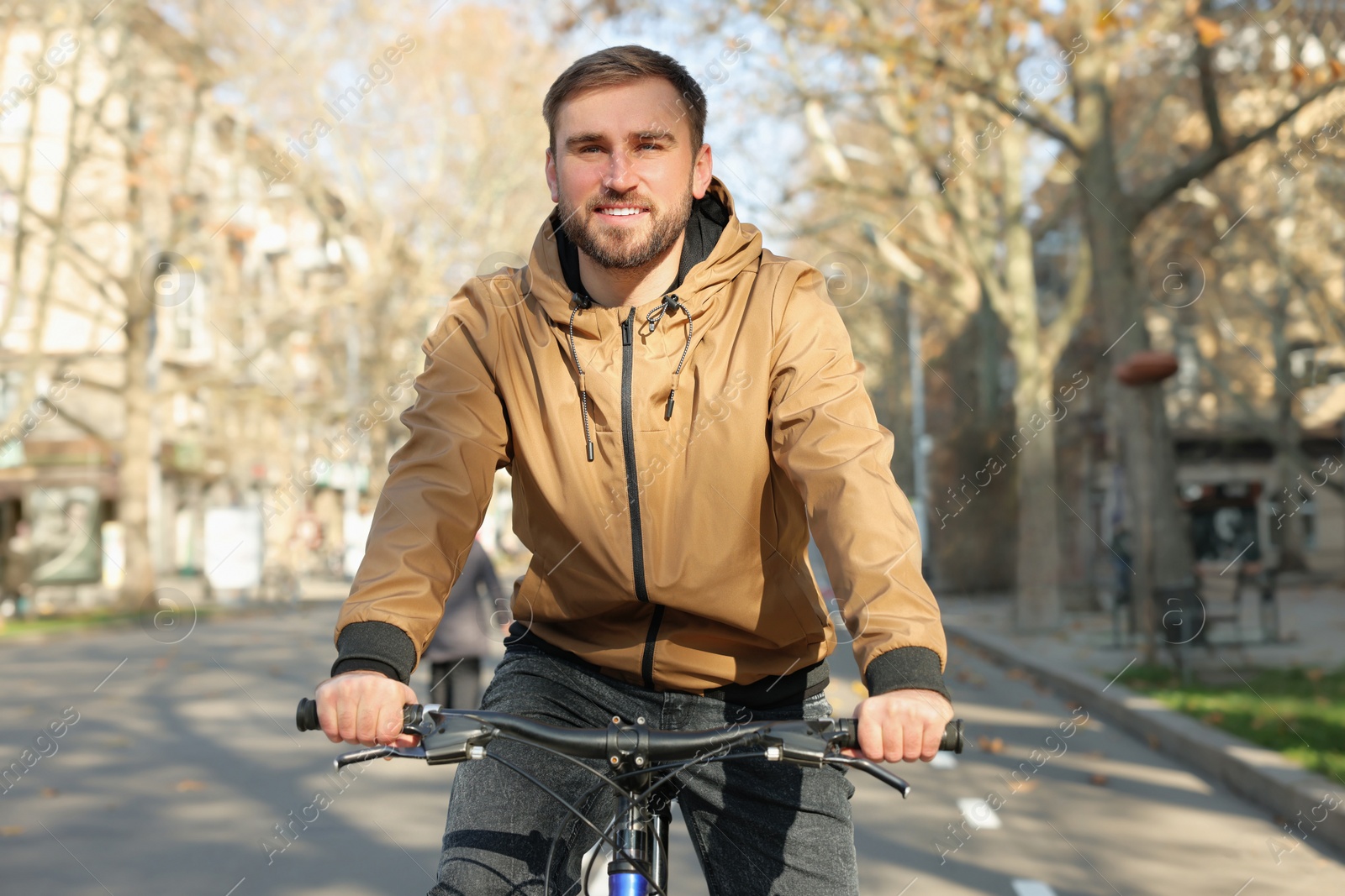 Photo of Happy handsome man riding bicycle on lane in city