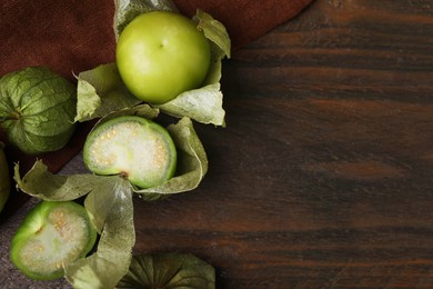 Fresh green tomatillos with husk on wooden table, flat lay. Space for text