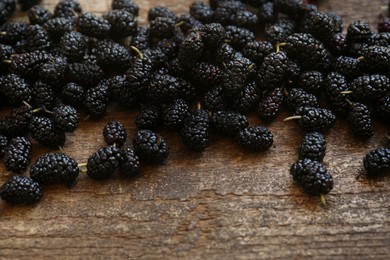 Heap of delicious ripe black mulberries on wooden table