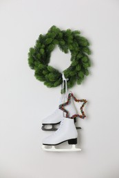 Photo of Pair of ice skates and Christmas wreath hanging on white wall