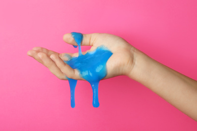 Woman playing with blue slime on pink background, closeup. Antistress toy
