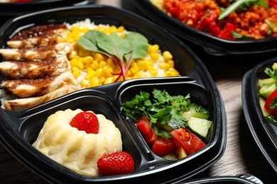 Photo of Lunchboxes with different meals on table, closeup. Healthy food delivery