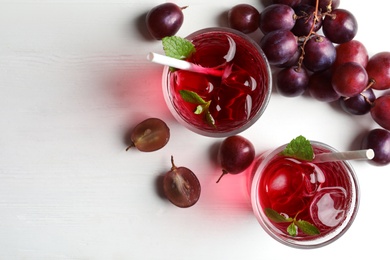 Photo of Delicious grape soda water and berries on white wooden table, flat lay. Refreshing drink