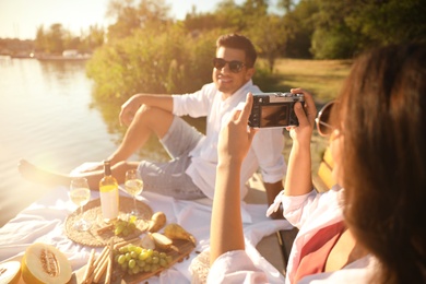 Photo of Woman taking picture of boyfriend on pier at picnic, closeup