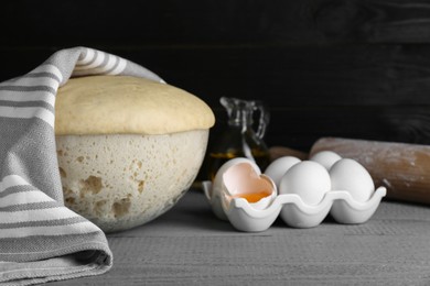 Photo of Fresh yeast dough and ingredients on grey wooden table