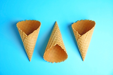 Photo of Empty wafer ice cream cones on blue background, flat lay