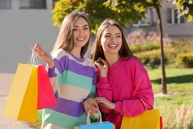 Photo of Beautiful young women with shopping bags on city street