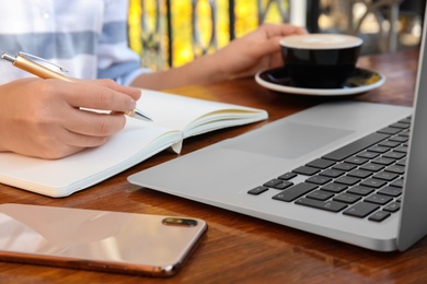 Photo of Woman writing blog content in notebook at table, closeup