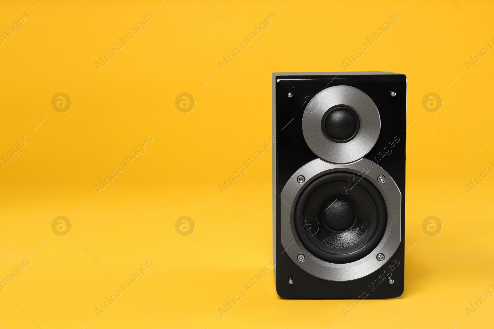 Photo of Modern powerful audio speaker on yellow background, space for text