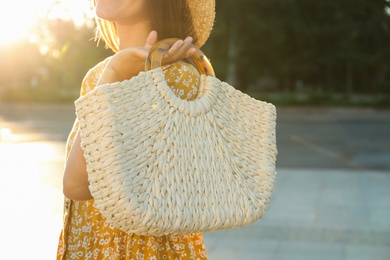 Photo of Young woman with stylish straw bag outdoors, closeup