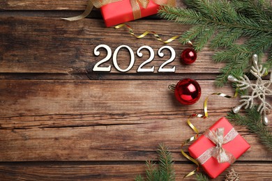 Photo of Happy New Year greeting card. Flat lay composition with 2022 numbers and festive decor on wooden background