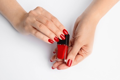 Photo of Woman with bright manicure holding bottle of nail polish on white background, closeup