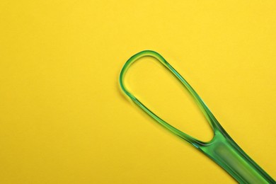 Photo of Green tongue cleaner on yellow background, top view. Space for text