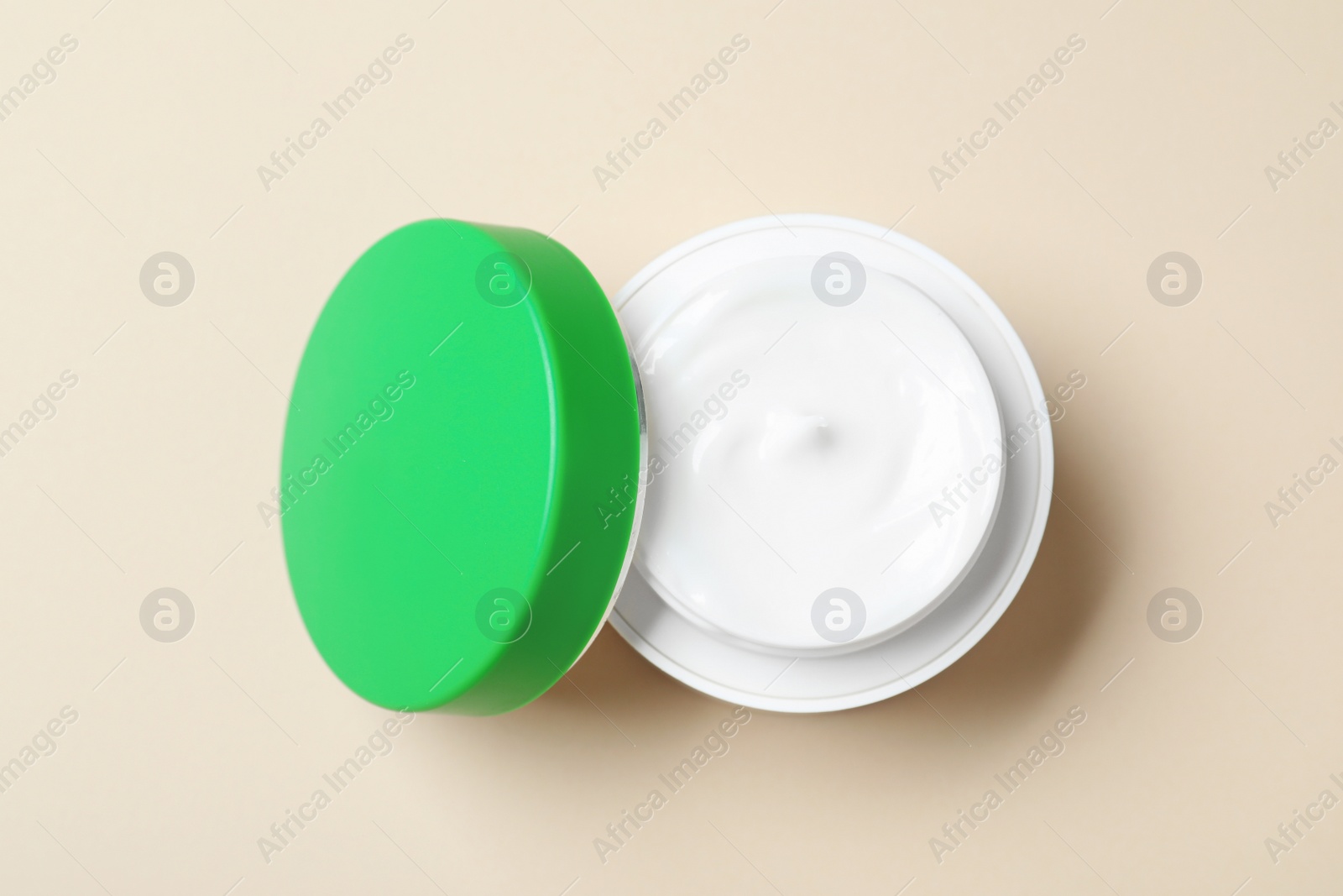 Photo of Open jar of cream on beige background, top view