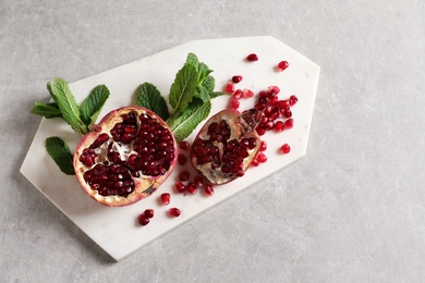 Board with ripe pomegranates and seeds on grey background, top view. Space for text