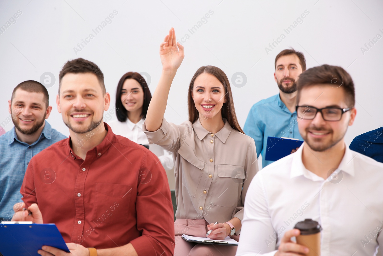 Photo of Young woman raising hand to ask question at business training on white background