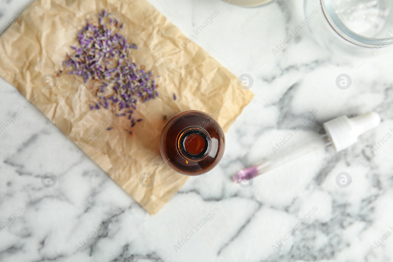 Photo of Natural herbal oil and lavender on marble background, top view