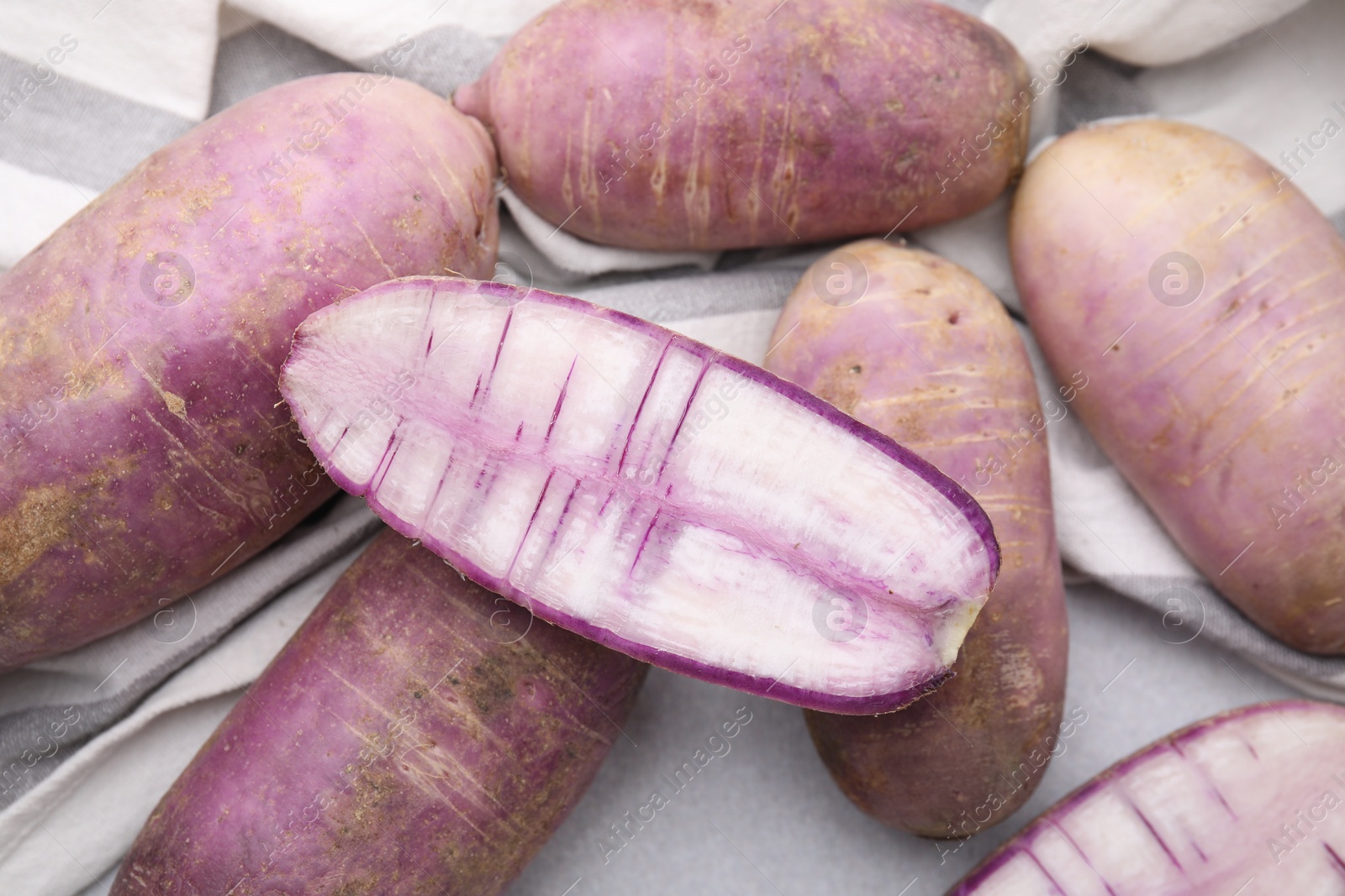 Photo of Purple daikon radishes on light grey table, closeup