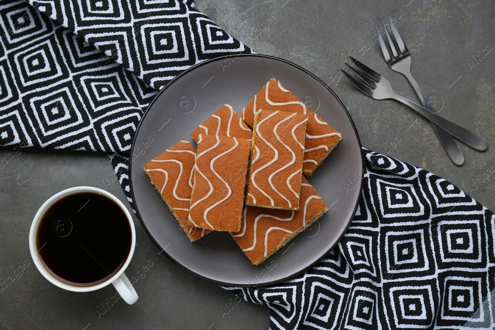 Photo of Tasty sponge cakes and hot drink on grey table, flat lay