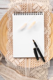 Guest list. Notebook, pen, spikelets and lace ribbons on wooden background, flat lay