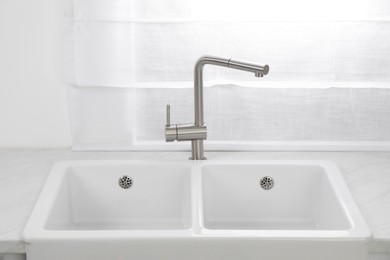 Modern sink and water tap near window in kitchen. Interior design