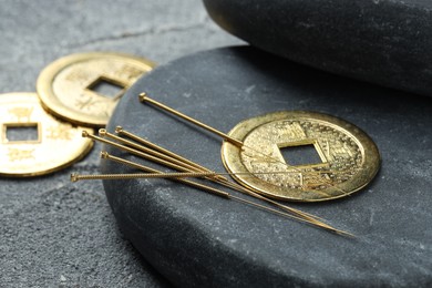 Photo of Acupuncture needles, Chinese coins and stone on grey textured table, closeup