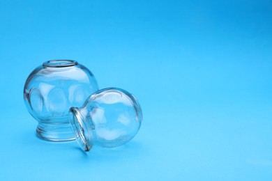 Photo of Glass cups on light blue background, space for text. Cupping therapy
