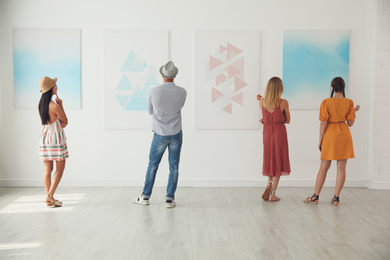 Group of people at exhibition in art gallery, back view