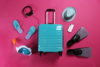 Flat lay composition with stylish suitcase and beach accessories on color background