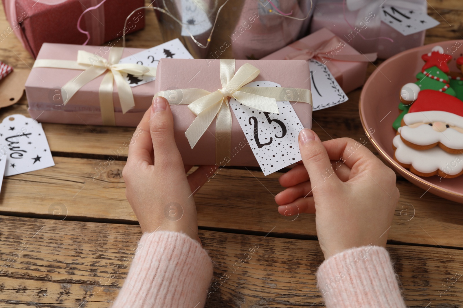 Photo of Woman making advent calendar at wooden table, closeup