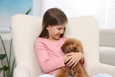 Photo of Little child with cute puppy in armchair at home. Lovely pet