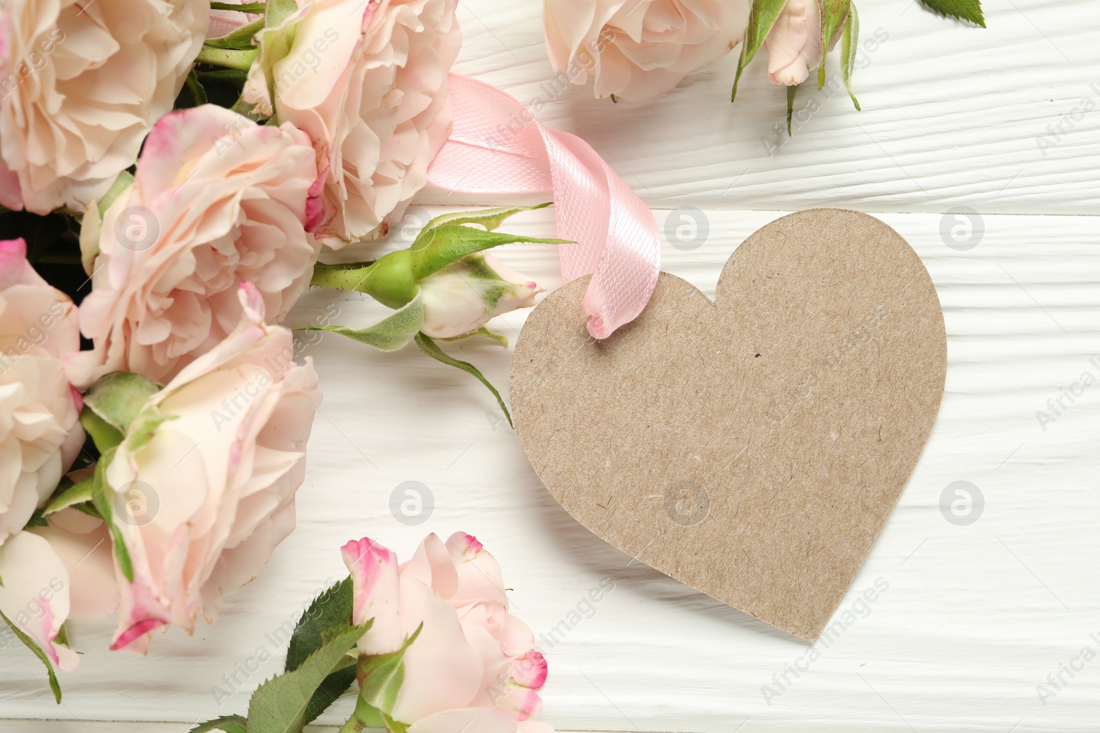 Photo of Happy Mother's Day. Beautiful flowers with blank heart shaped card on white wooden table, closeup