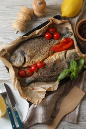 Delicious roasted dorado fish served on wooden table, flat lay