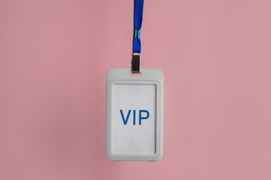Photo of Plastic vip badge hanging on pale pink background