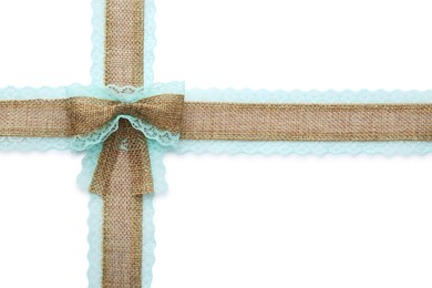 Burlap ribbons and bow with light blue lace on white background, top view