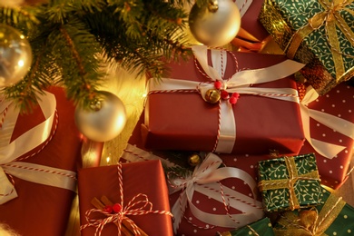 Pile of gift boxes near Christmas tree, above view