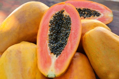 Photo of Fresh ripe cut and whole papaya fruits on wooden table, closeup