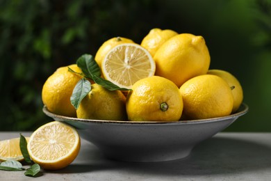 Fresh lemons and green leaves on grey table outdoors, closeup